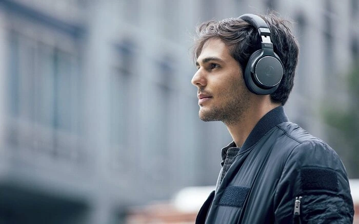 Imagen llamada a la acción tienda online Audiophile joven chico sonriente con unos auriculares negros marca AUDIOPHILE